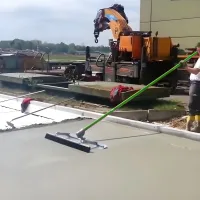 Metex Fresno broom with trowel, bull float bracket and swaged handle in use on a concrete slab